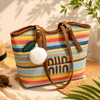 Colorful striped handbag with 'Umi' branding on a surface with a plant and hat in the background.