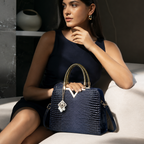Woman holding a blue handbag with gold accents in an indoor setting