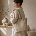 Woman holding a beige tote bag with 'Canteen Roma' branding in a warm, indoor setting.