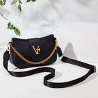 Black handbag with gold chain detail on a light background