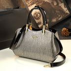 Gray handbag with black accents on a reflective surface