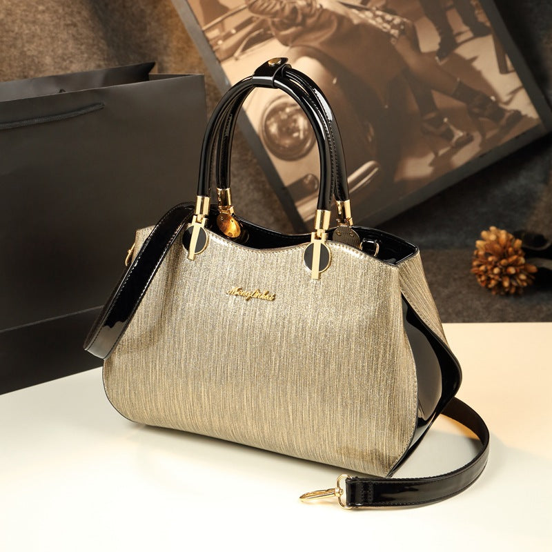 Gold handbag with black accents on a white surface, with a blurred background