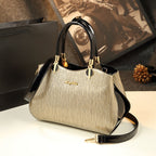 Gold handbag with black accents on a white surface, with a blurred background