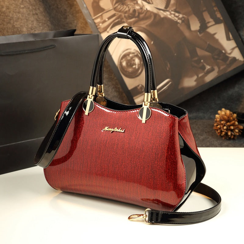 Red handbag with black handle and strap on a white surface, blurred background
