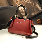 Red handbag with black handle and strap on a white surface, blurred background